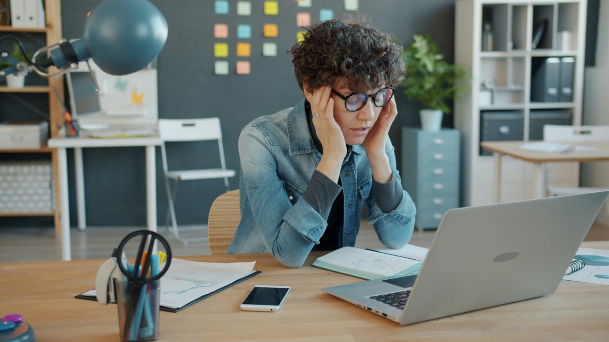 Burned out therapist overwhelmed at desk with laptop